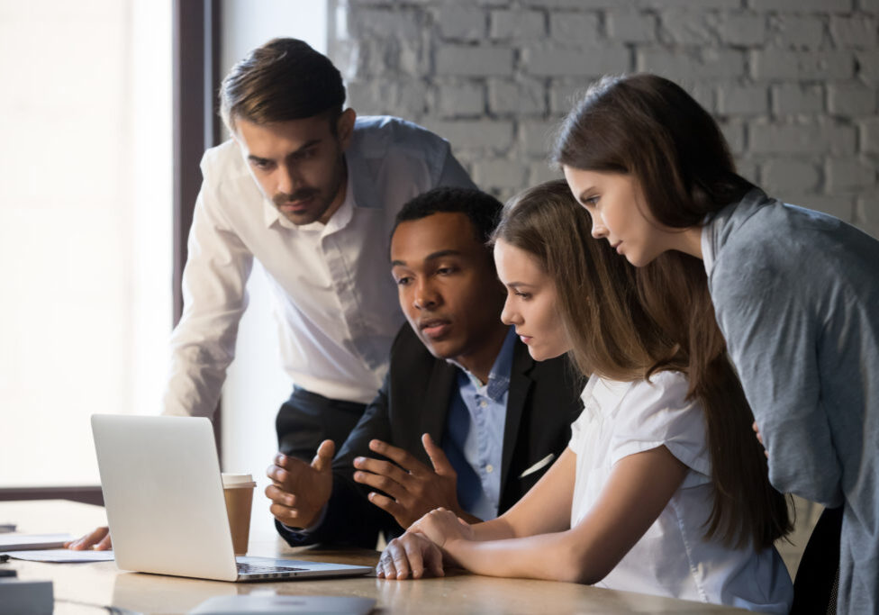 Diverse,Millennial,Workers,Cooperating,,Working,Together,At,Laptop,Discussing,Business